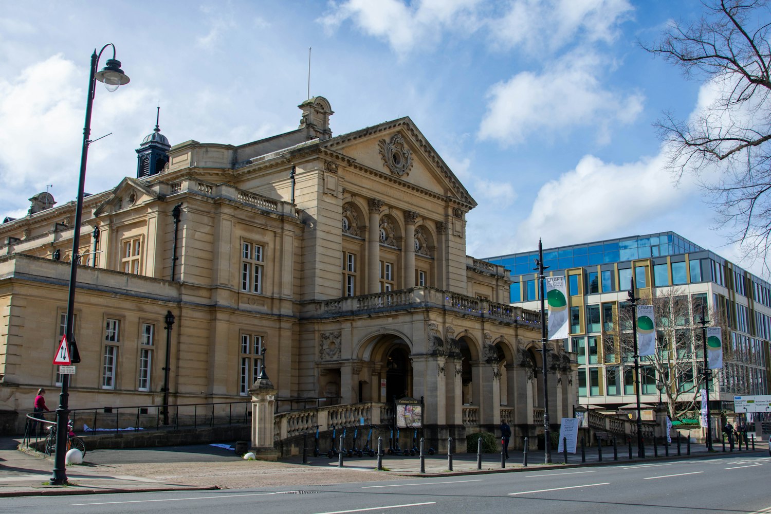 A historic county courthouse on a city street, with people at tables in the plaza outside.